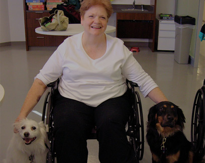 women in wheelchair visiting with two dogs